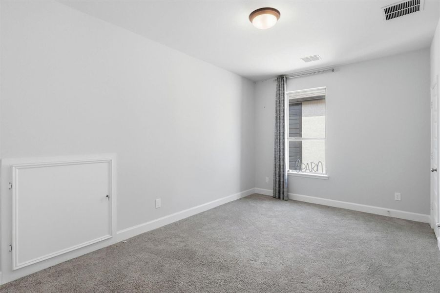 This secondary bedroom offers plush carpeting, soft natural light, and a spacious layout that easily accommodates a full bedroom suite. Neutral finishes provide the perfect backdrop for any style.