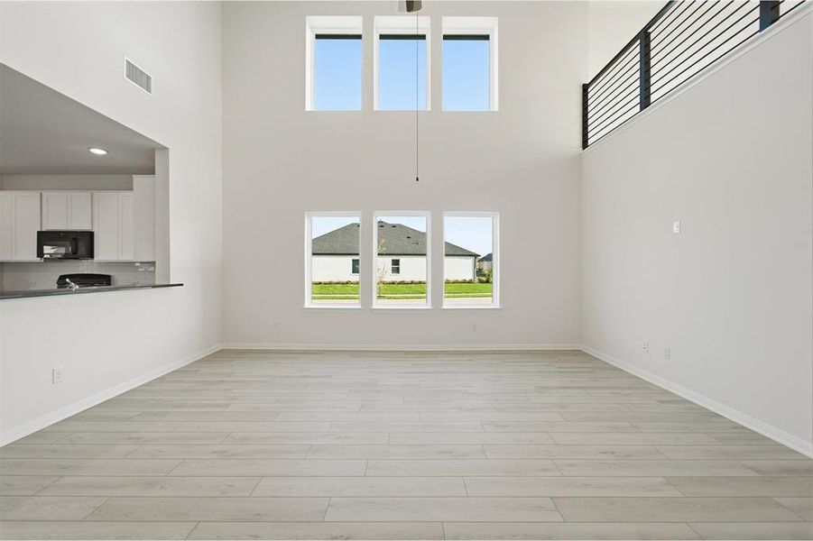 Spacious living area featuring light wood-finish flooring and high ceilings
