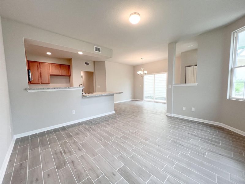 Unfurnished living room with wood tiled floors and hanging lights