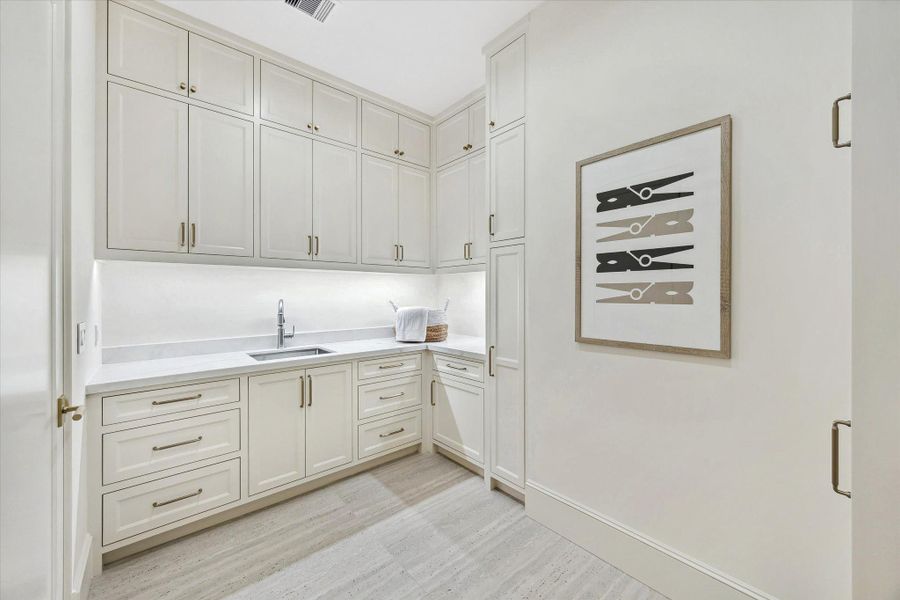 Utility room featuring a deep sink, extensive built-in cabinetry and generous counter space. Travertine tile. Utility room featuring a deep sink, extensive built-in cabinetry and generous counter space. Travertine tile.