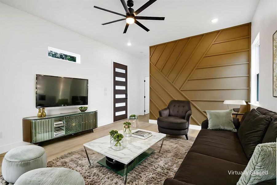 Living area with wood finished floors, a ceiling fan, recessed lighting, and a decorative wall