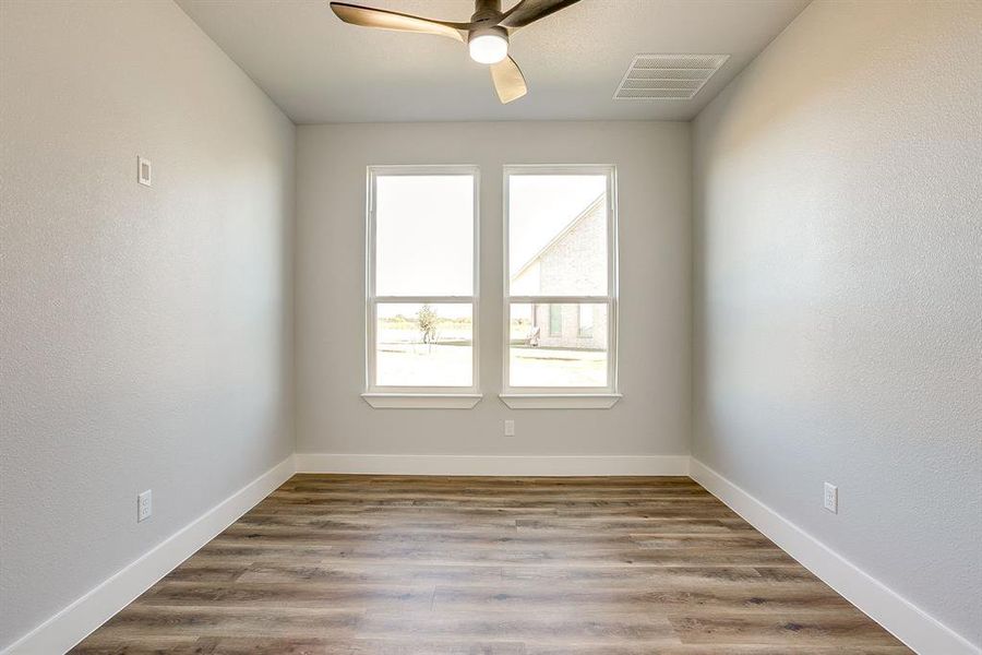 Spare room with a textured wall, light wood-style flooring, and a ceiling fan