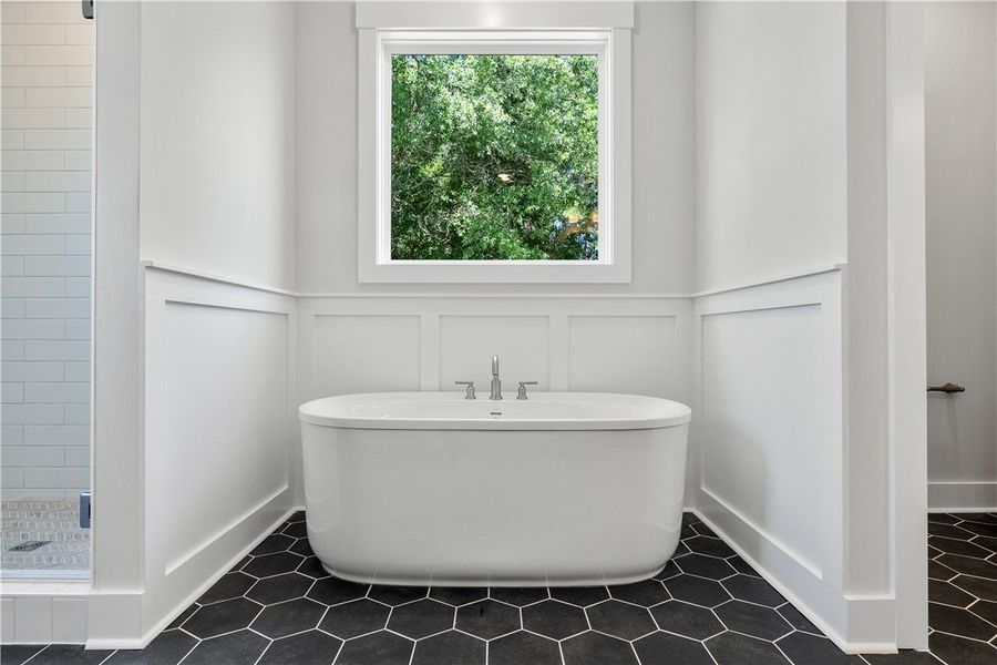 A deep soaking tub sits gracefully against a panel