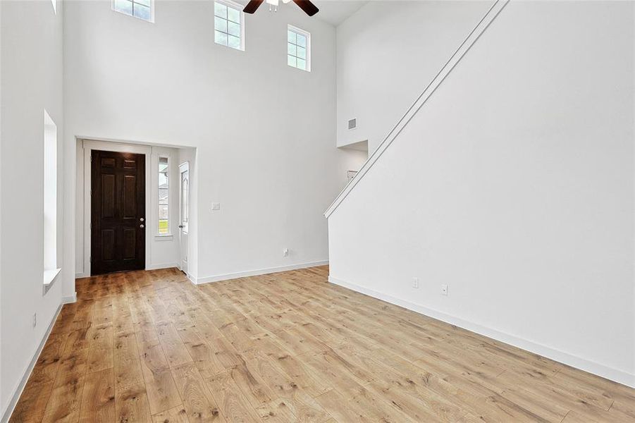 Foyer entrance with ceiling fan, a towering ceiling, and light hardwood / wood-style floors