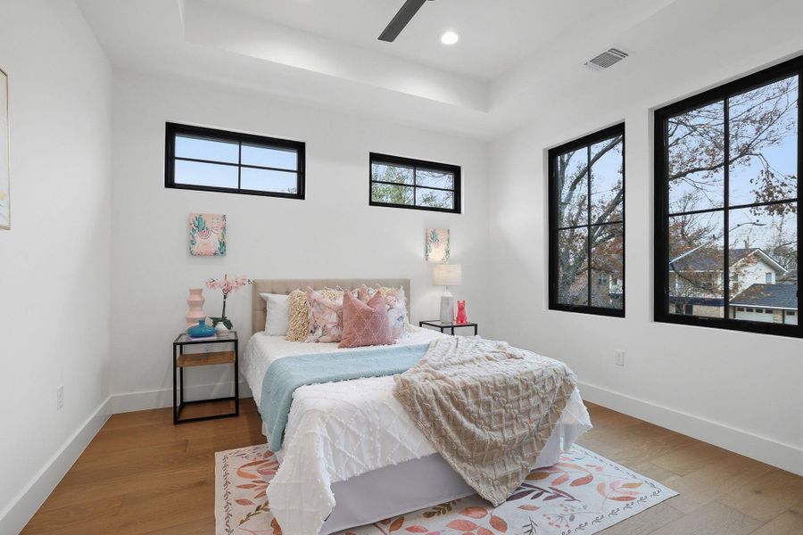 Bedroom featuring a raised ceiling, wood finished floors, a ceiling fan, and recessed lighting