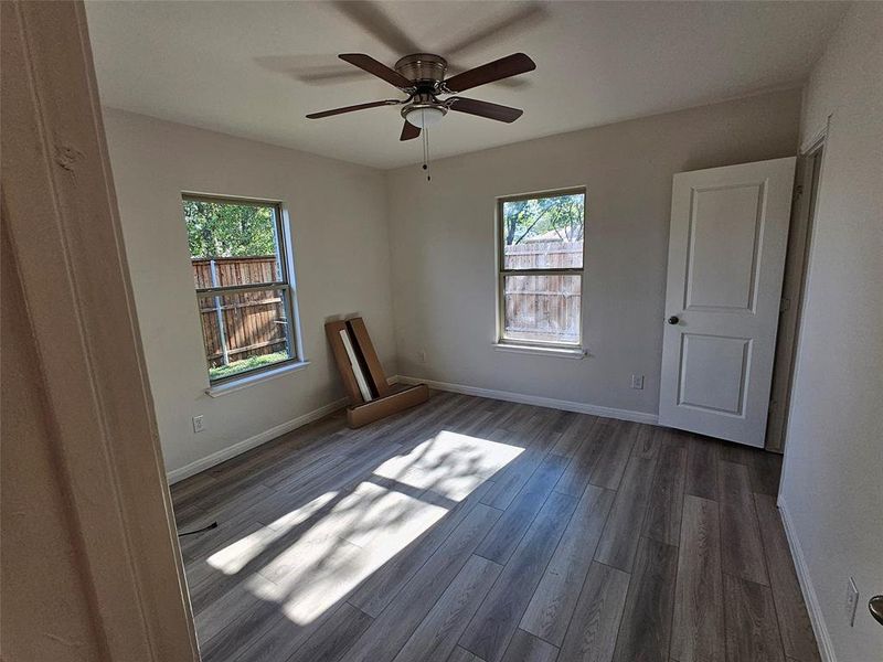 Empty room with dark wood-type flooring and ceiling fan