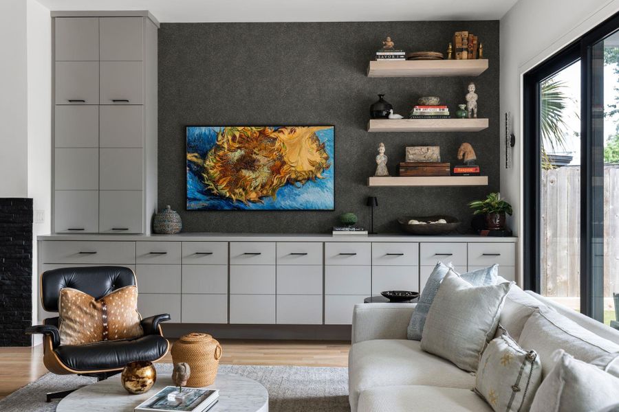 A built-in media wall with textured accent wallpaper anchors the room while custom cabinetry and floating display shelves add both style and practical storage to the family room.