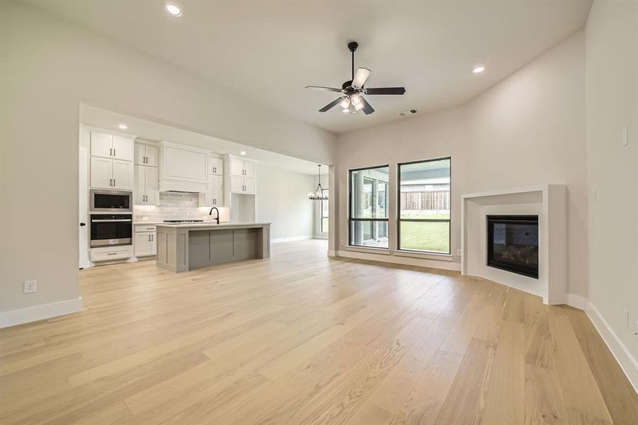 Unfurnished living room featuring light wood-style flooring, recessed lighting, a ceiling fan, and a glass covered fireplace Unfurnished living room featuring light wood-style flooring, recessed lighting, a ceiling fan, and a glass covered fireplace