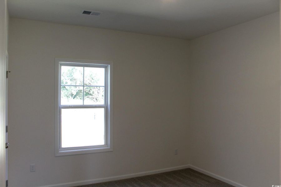 Empty room with dark colored carpet and baseboards