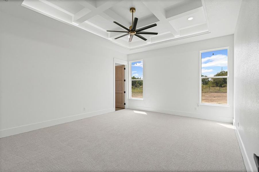 Spare room featuring coffered ceiling, healthy amount of natural light, carpet floors, beamed ceiling, and ceiling fan Spare room featuring coffered ceiling, healthy amount of natural light, carpet floors, beamed ceiling, and ceiling fan