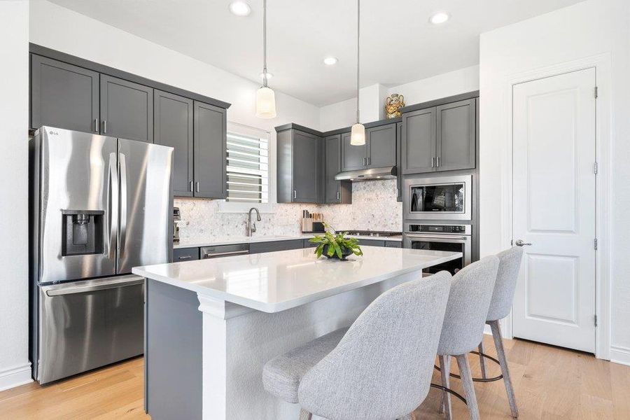 Streamlined cabinetry and premium quartz countertops define this modern culinary workspace with light hardwood floors. Streamlined cabinetry and premium quartz countertops define this modern culinary workspace with light hardwood floors.