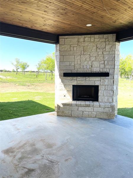 View of patio outdoor stone fireplace with hearth and mantle