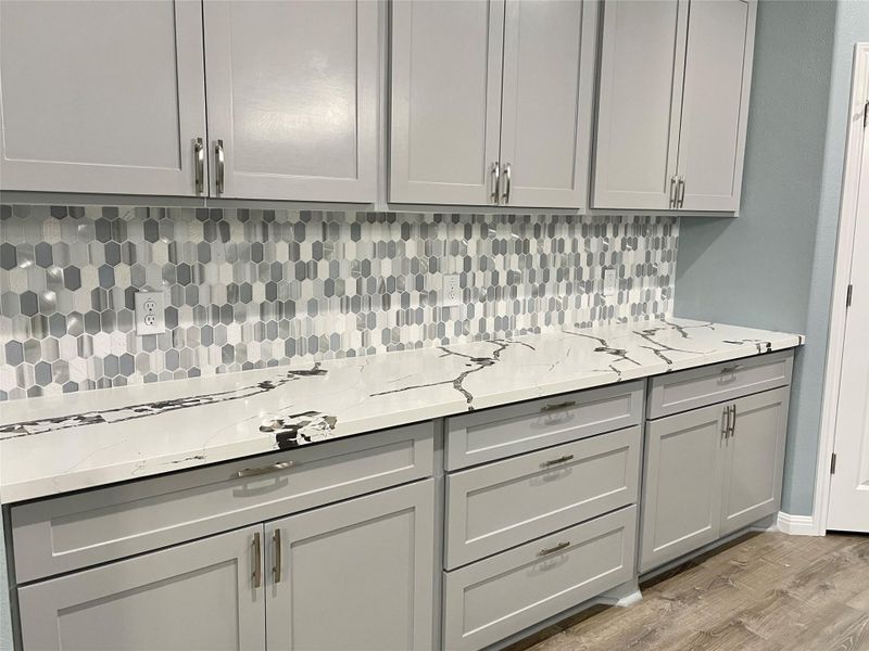 Crisp white counters and a geometric tiled backsplash highlight this well-appointed kitchen space.