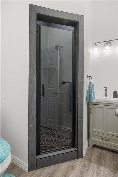 Bathroom with sink, hardwood / wood-style floors, an enclosed shower, and toilet