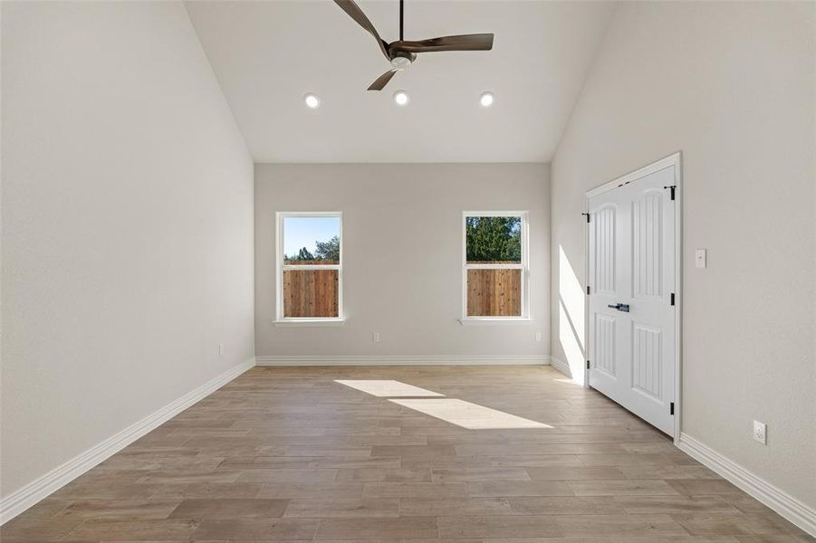 Empty room with ceiling fan, high vaulted ceiling, and light hardwood / wood-style floors