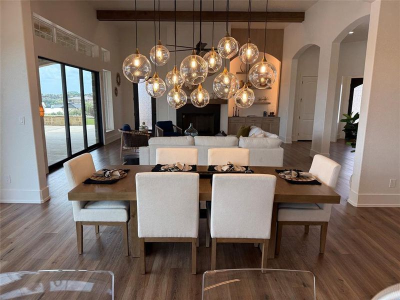 Dining space featuring beam ceiling, arched walkways, wood finished floors, and a high ceiling Dining space featuring beam ceiling, arched walkways, wood finished floors, and a high ceiling