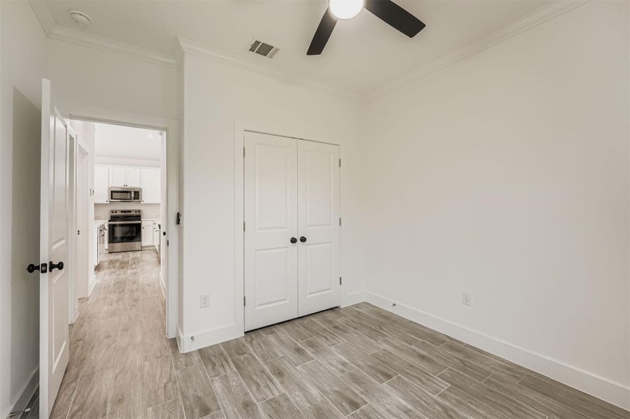Bedroom 2 featuring wood-style vinyl plank flooring, a closet and a view into the bright kitchen area Bedroom 2 featuring wood-style vinyl plank flooring, a closet and a view into the bright kitchen area