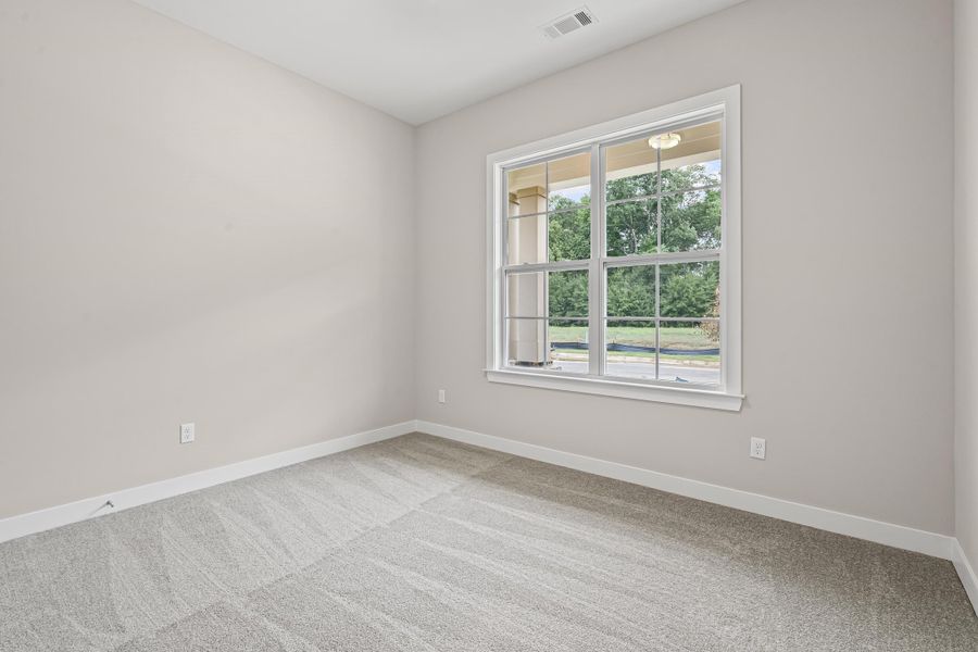 Carpeted spare room featuring baseboards