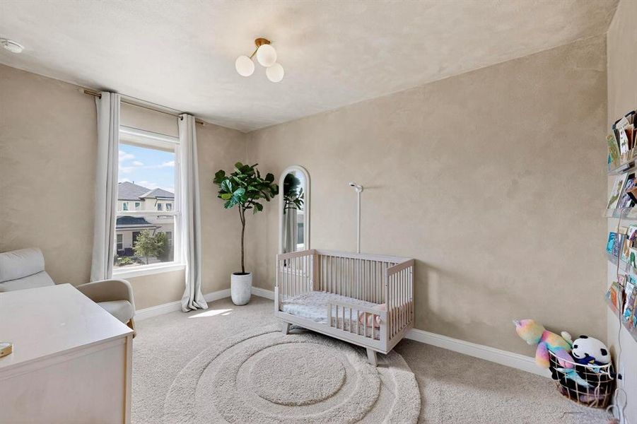 Carpeted bedroom with a crib and baseboards Carpeted bedroom with a crib and baseboards