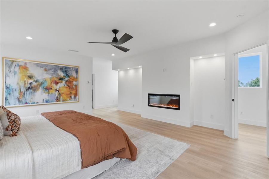 Open interior space featuring wood-finish flooring, a contemporary ceiling fan, recessed lighting, and a linear electric fireplace Open interior space featuring wood-finish flooring, a contemporary ceiling fan, recessed lighting, and a linear electric fireplace