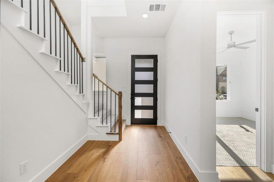 Foyer entrance featuring stairway, wood finished floors, visible vents, and baseboards