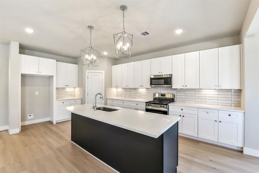 Stylish kitchen with white cabinetry, a sleek tile backsplash and large center island perfect for prep and gathering.