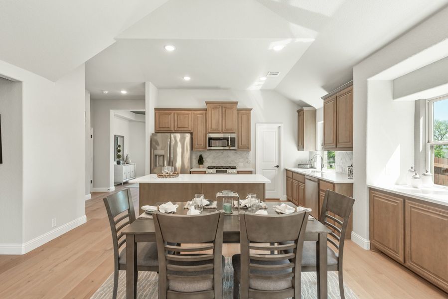 Open dining area with six-seat table flowing into kitchen with brown cabinets and center island