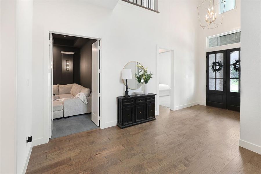 Two-story foyer featuring dark wood-finish flooring, a contemporary chandelier, and a transom window above double black entry doors
