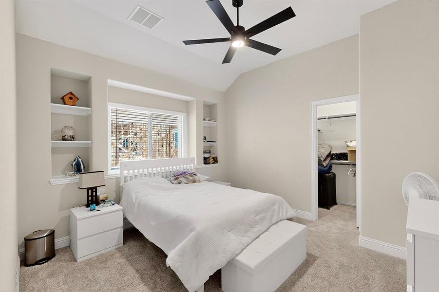 Bedroom featuring a walk in closet, light colored carpet, ceiling fan, and vaulted ceiling Bedroom featuring a walk in closet, light colored carpet, ceiling fan, and vaulted ceiling