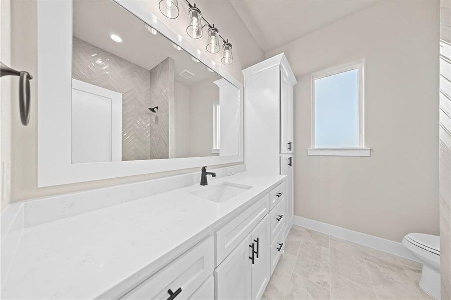 Bathroom with vanity, tiled shower, and light tile patterned flooring