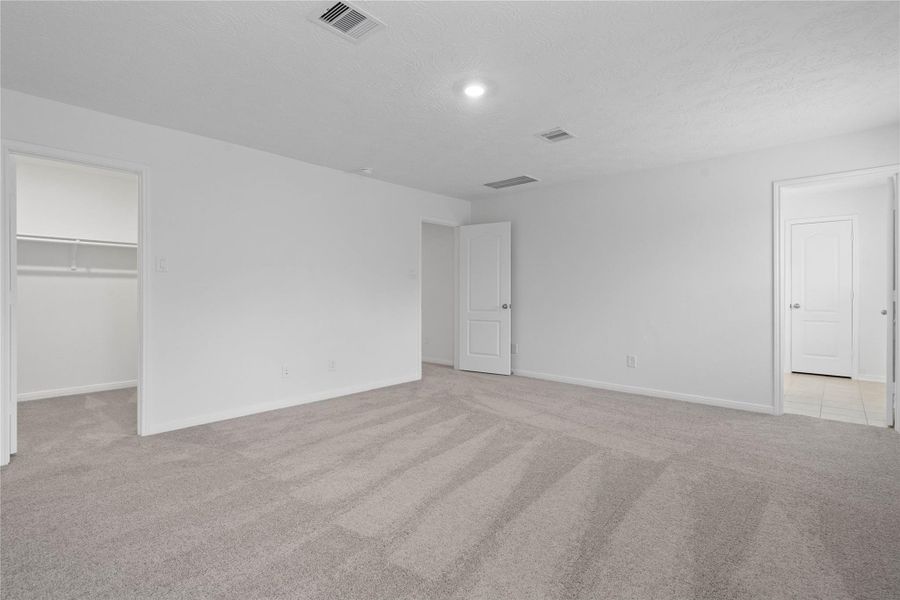 View of primary bedroom looking towards walk-in closet and ensuite bathroom.