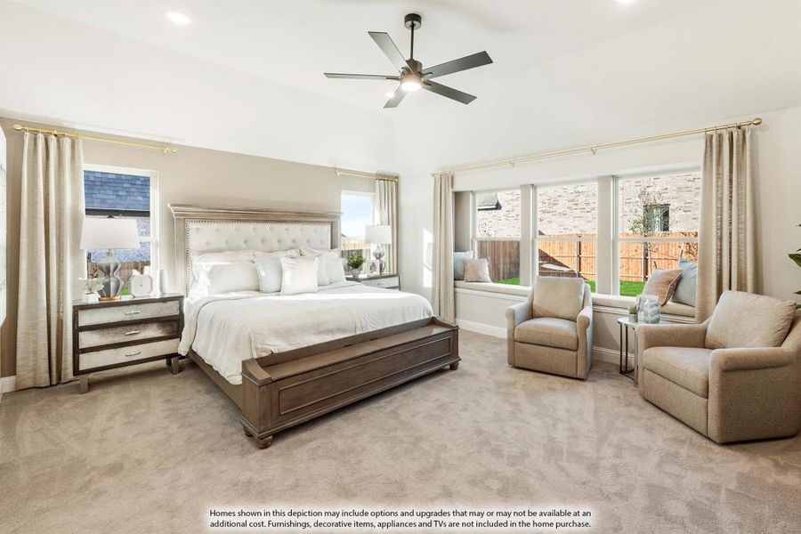 Spacious master bedroom with king bed, ceiling fan, window seat, and two sitting chairs on carpet flooring