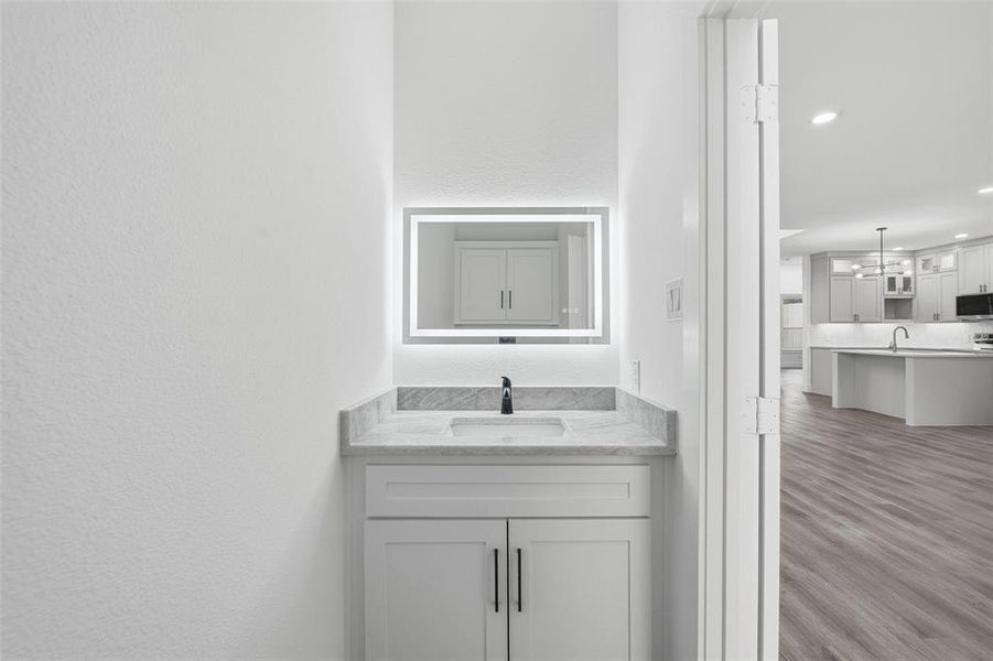 Bathroom with vanity, dark wood-style floors, recessed lighting, and a textured wall
