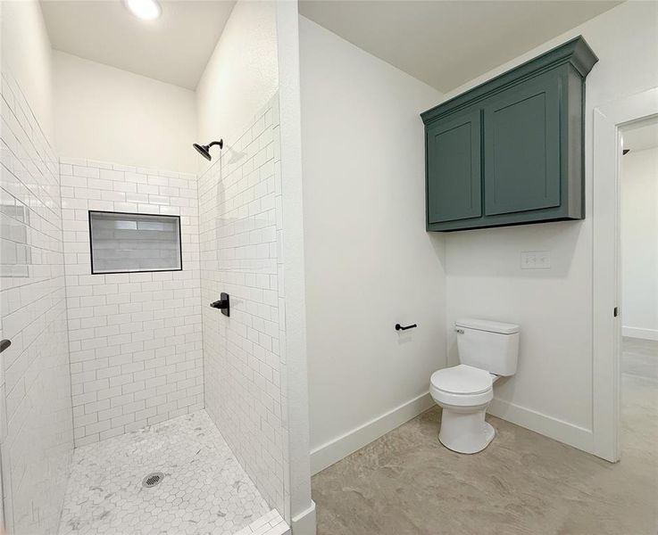 Full bathroom featuring tiled shower, baseboards, and toilet Full bathroom featuring tiled shower, baseboards, and toilet