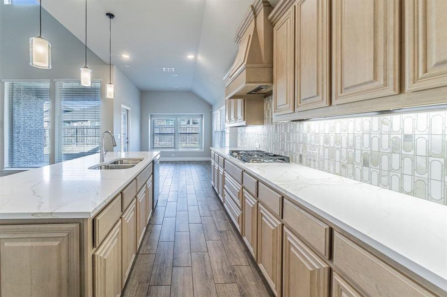 Kitchen featuring light wood-finish cabinetry, white countertops, a gas cooktop, and a decorative tile backsplash