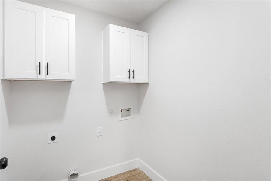 Clothes washing area with washer hookup, gas dryer hookup, cabinets, light wood-type flooring, and electric dryer hookup