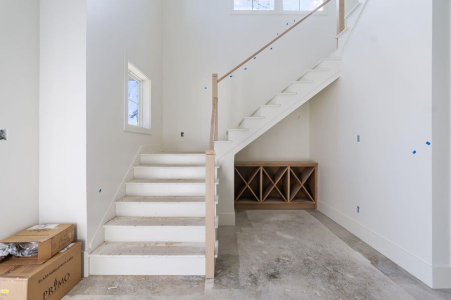 Entry view featuring the staircase and custom built in storage beneath, adding function and architectural detail right as you walk in.