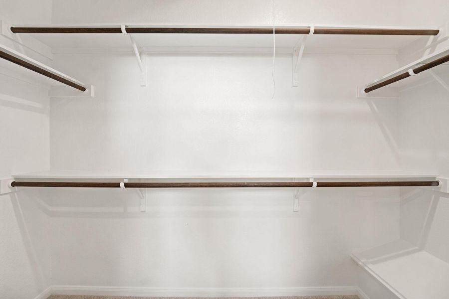 Double hanging rods and integrated overhead shelving maximize storage potential in this walk-in closet.