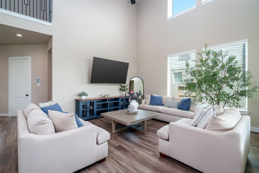 The spacious living room boasts soaring high ceilings, beautiful LVP flooring, and large windows with privacy blinds that fill the space with natural light while maintaining comfort and seclusion. The spacious living room boasts soaring high ceilings, beautiful LVP flooring, and large windows with privacy blinds that fill the space with natural light while maintaining comfort and seclusion.