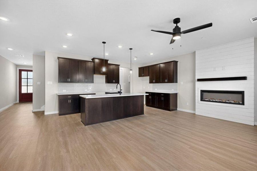 Kitchen featuring tasteful backsplash, dark brown cabinetry, a kitchen island with sink, light wood-style floors, and recessed lighting Kitchen featuring tasteful backsplash, dark brown cabinetry, a kitchen island with sink, light wood-style floors, and recessed lighting