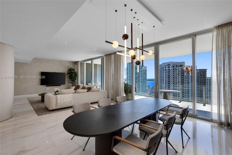 Floor-to-ceiling glass walls, polished stone flooring, custom multi-light chandelier, and recessed lighting