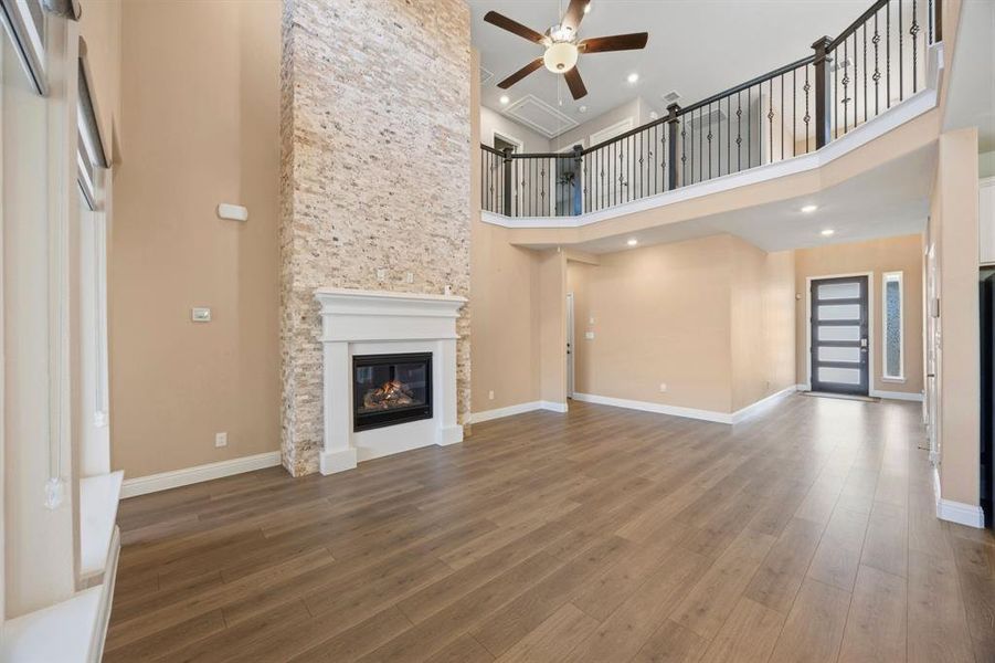 1st level living room featuring high ceilings, ceiling fan, and gas fireplace. Stone on the fire place is custom.