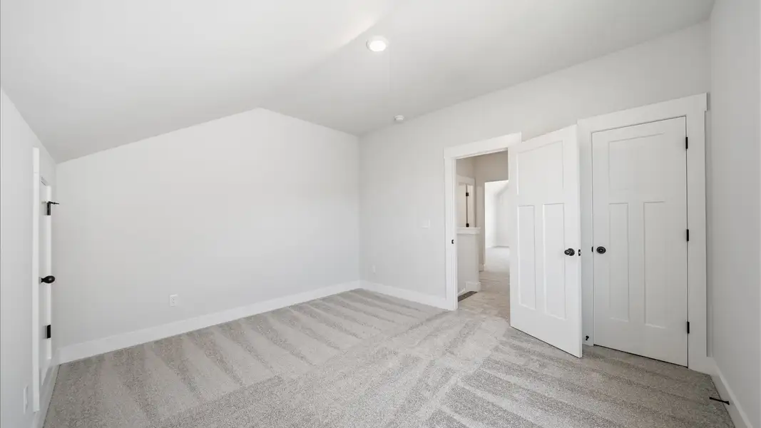 First-class secondary bedroom with comfortable carpeted flooring and generous closet space at the Iris Meadows community