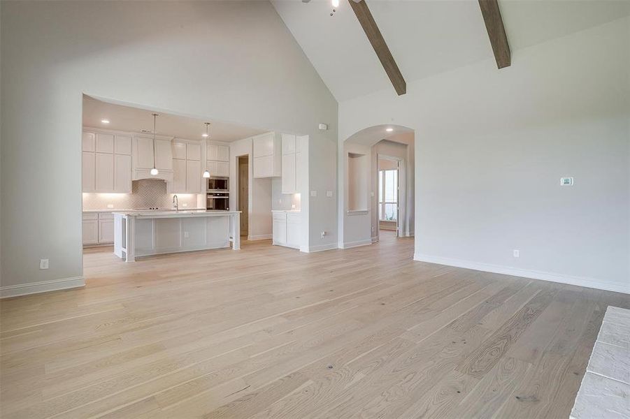 Unfurnished living room with light hardwood / wood-style flooring, high vaulted ceiling, and beamed ceiling