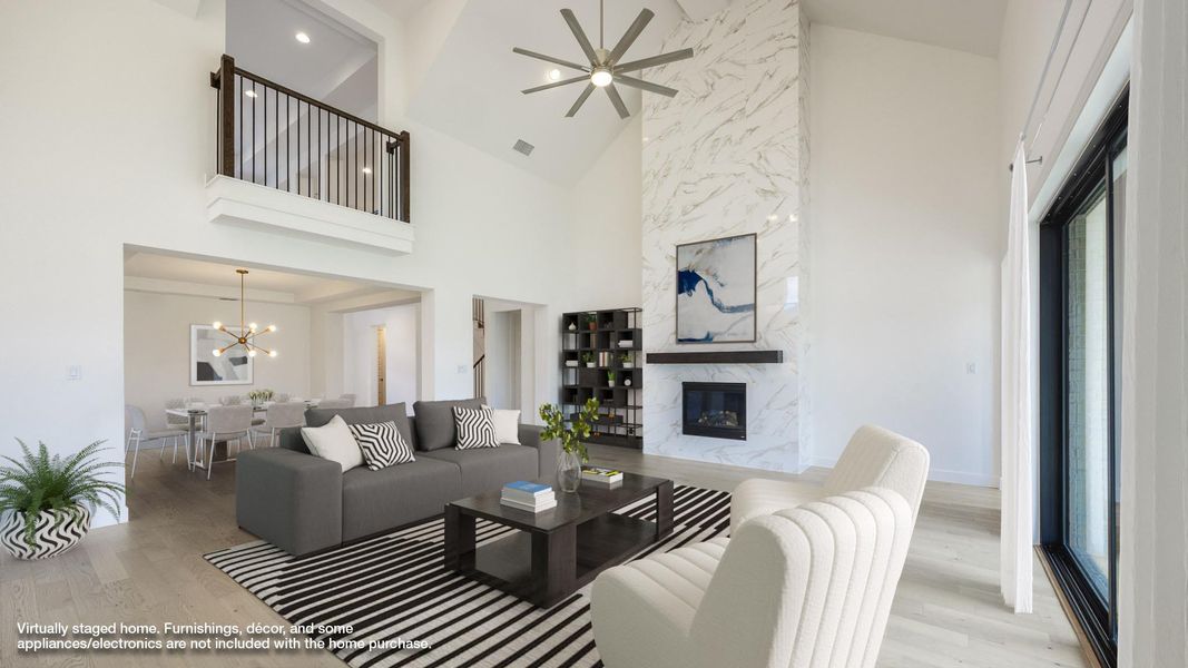 Living room featuring light wood finished floors, high vaulted ceiling, a high end fireplace, a ceiling fan, and a chandelier Living room featuring light wood finished floors, high vaulted ceiling, a high end fireplace, a ceiling fan, and a chandelier