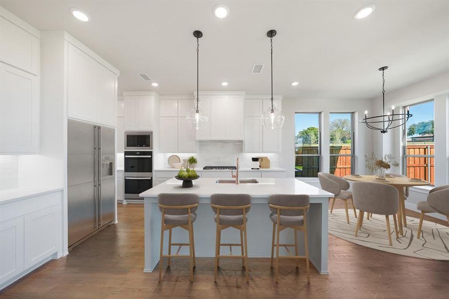 Kitchen featuring appliances with stainless steel finishes, pendant lighting, white cabinets, a center island with sink, and recessed lighting Kitchen featuring appliances with stainless steel finishes, pendant lighting, white cabinets, a center island with sink, and recessed lighting