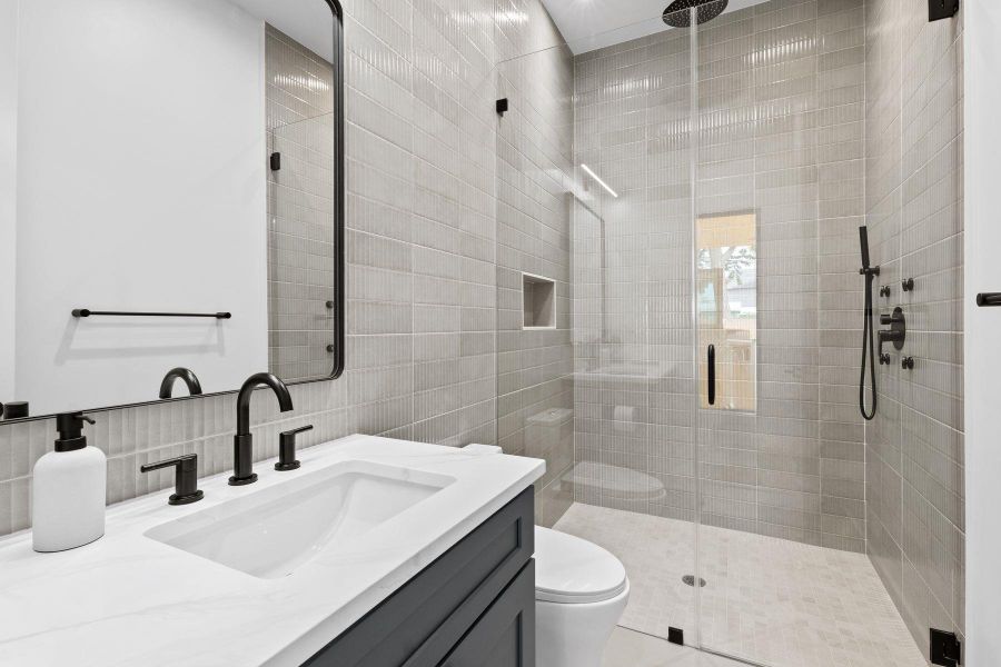 A chic primary bathroom showcases a glass-enclosed shower, rain shower head, and an elegant vanity with a marble counter. A chic primary bathroom showcases a glass-enclosed shower, rain shower head, and an elegant vanity with a marble counter.