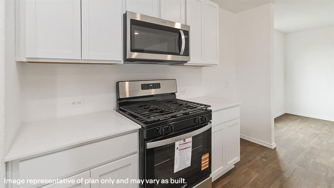 Kitchen featuring appliances with stainless steel finishes, white cabinets, dark wood finished floors, and light stone counters