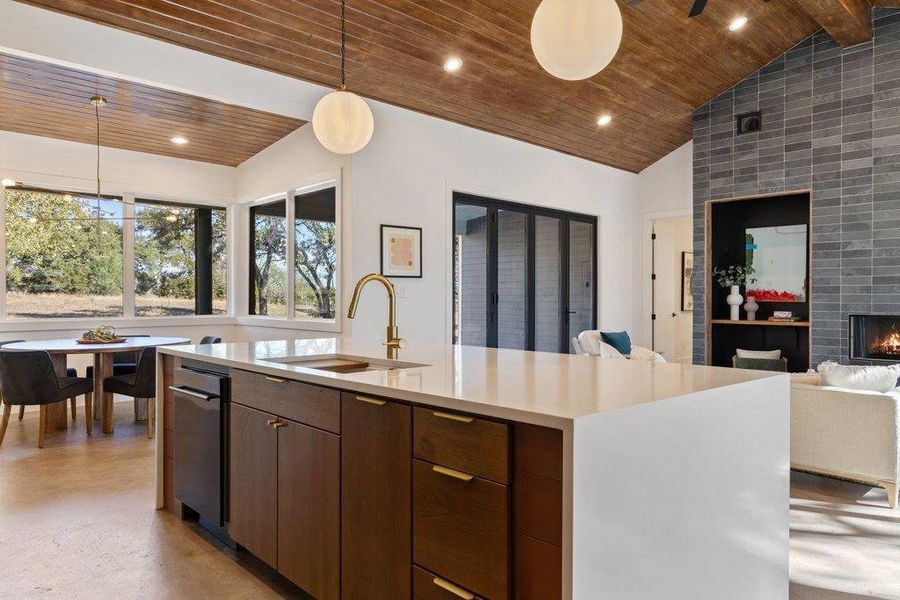 Kitchen with modern cabinets, hanging light fixtures, a fireplace, wood ceiling, and open floor plan