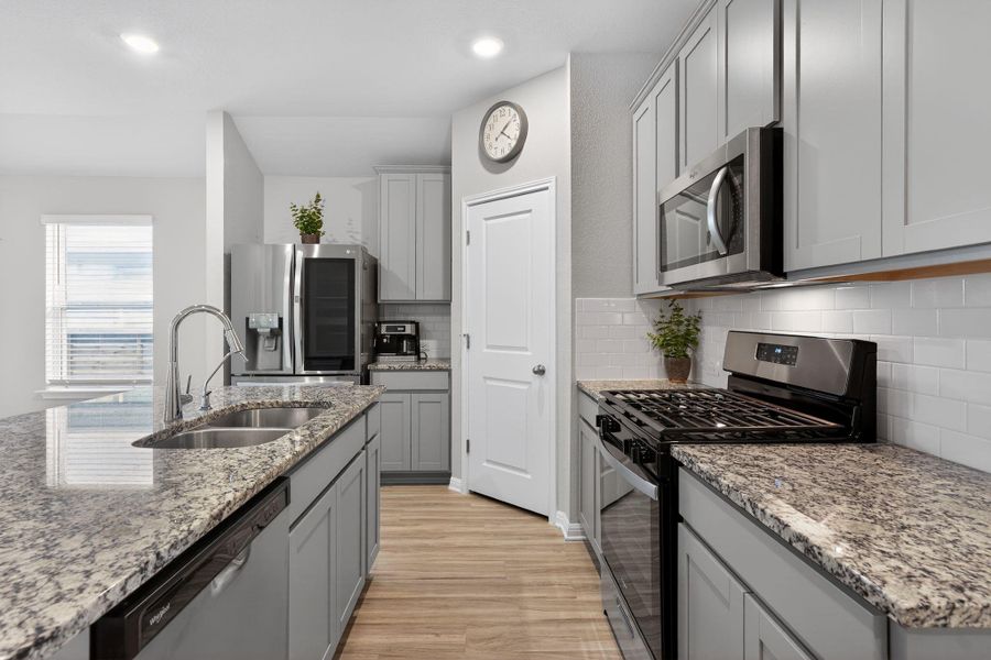 Kitchen featuring stainless steel appliances, gray cabinetry, light wood-style flooring, light stone counters, and recessed lighting